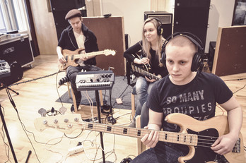 Tre elever musicerar. Två av dem har hörlurar på.