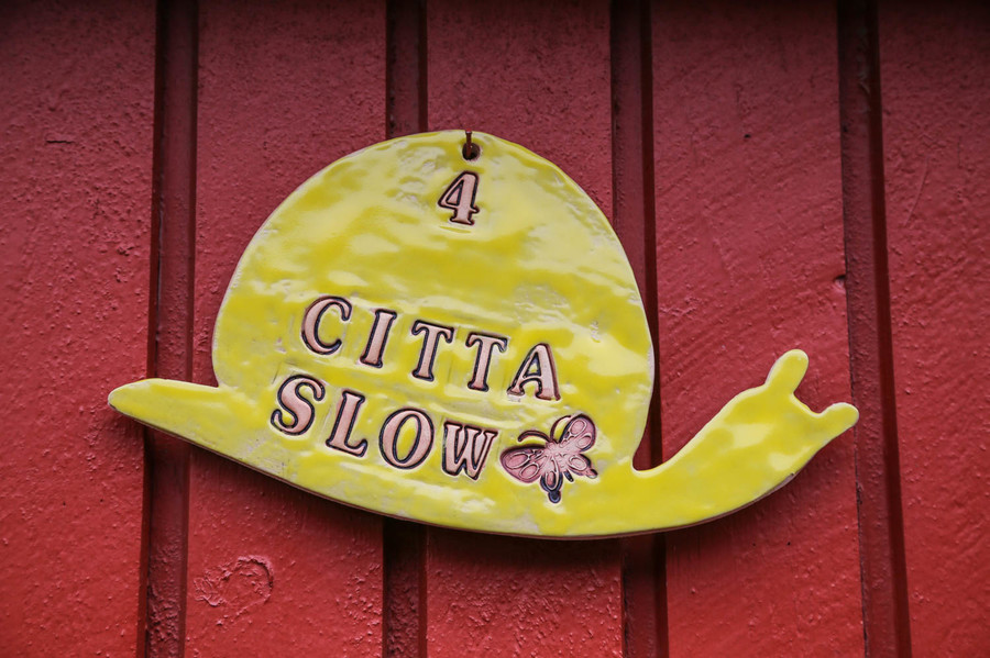 Cittaslow-symbolen hänger på en röd trävägg.