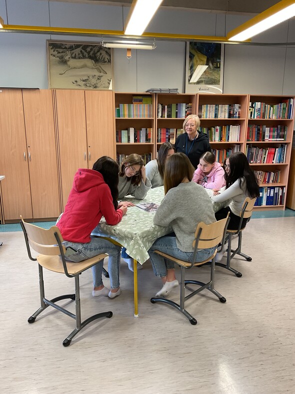 bild av elever som jobbar tillsammans kring ett bord under lärarens övervakning