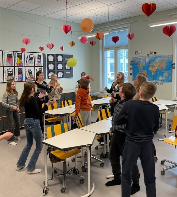 elever i klassrummet håller tre ballonger i rörelse