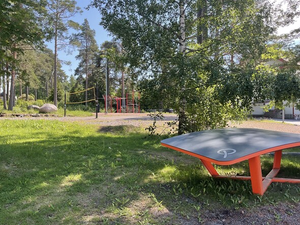 Kuva vihreästä koulupihasta missä on punainen pelipöytä ja lentopallokenttä 
